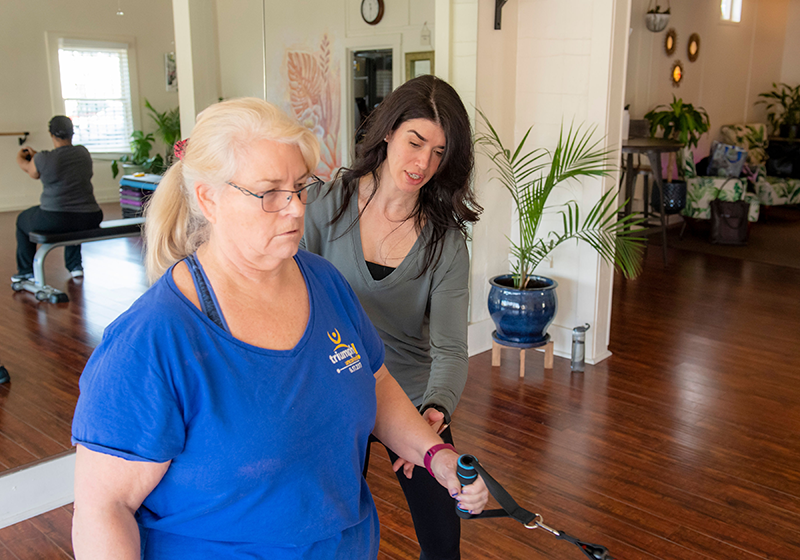 A fitness instructor helping a cancer survivor to rebuild her strength after treatment