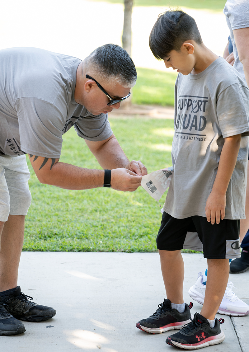 A dad helps his son put on his racing bib at a Parkinson's benefit walk